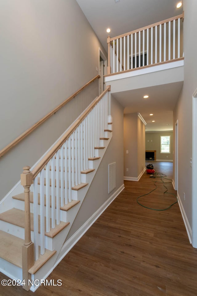 stairway with a high ceiling and hardwood / wood-style flooring