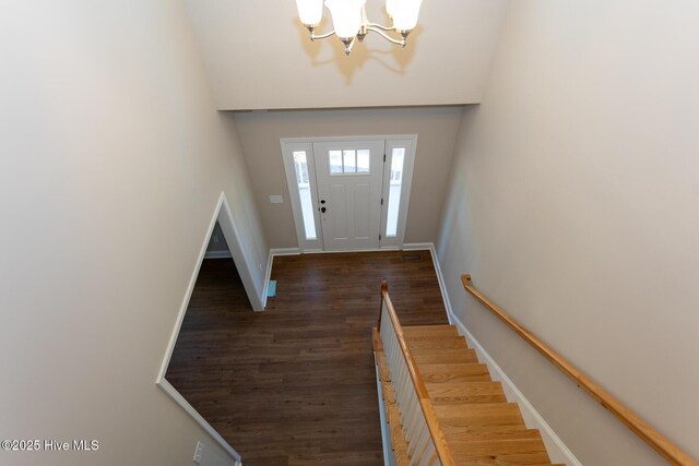 corridor featuring a healthy amount of sunlight, dark hardwood / wood-style floors, and an inviting chandelier