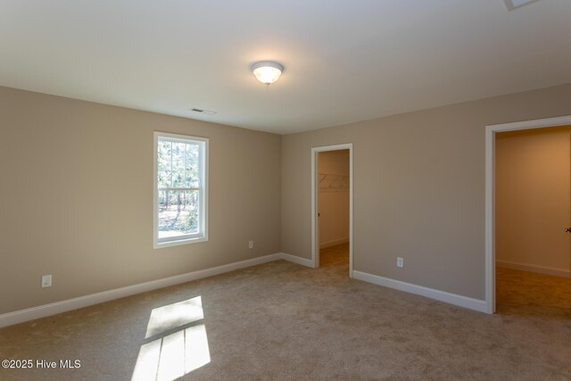 unfurnished bedroom featuring light carpet, a spacious closet, and a closet