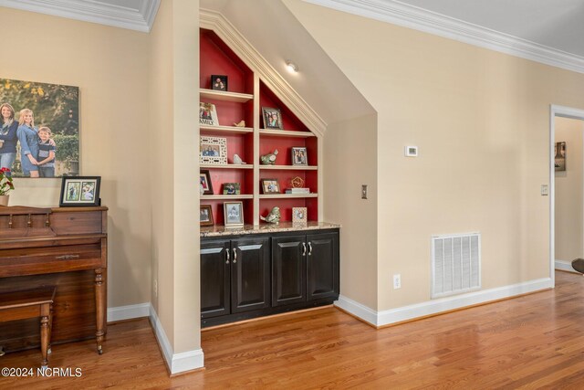 bar with built in shelves, visible vents, wood finished floors, and ornamental molding