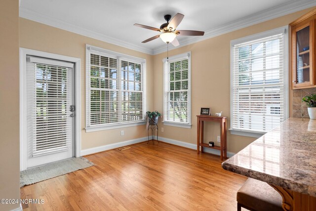 dining area with light wood finished floors, plenty of natural light, ceiling fan, and crown molding