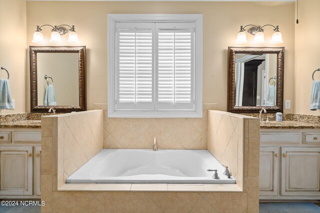 bathroom featuring two vanities, a garden tub, and a sink