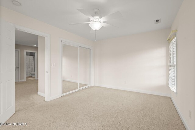 unfurnished bedroom with light carpet, a closet, visible vents, and baseboards