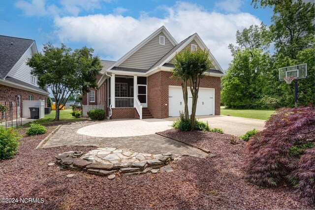 view of front of house with a garage, a sunroom, concrete driveway, and brick siding