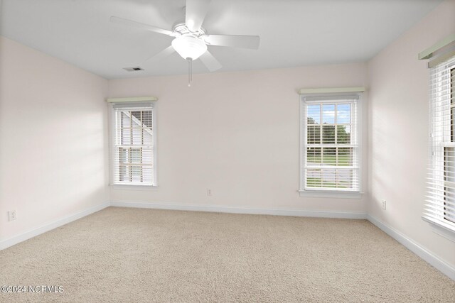 carpeted empty room featuring ceiling fan, visible vents, and baseboards