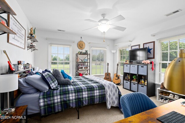 carpeted bedroom with a ceiling fan, visible vents, and multiple windows