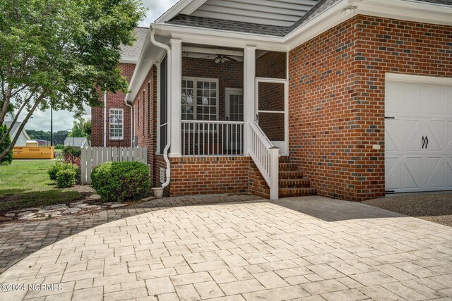 entrance to property with a garage, brick siding, fence, and a shingled roof