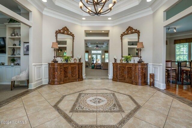 entrance foyer featuring plenty of natural light, a tray ceiling, and crown molding