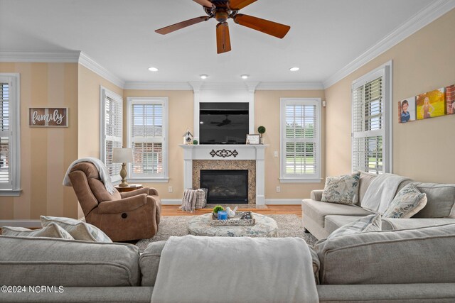 living area with a fireplace, recessed lighting, ornamental molding, wood finished floors, and baseboards