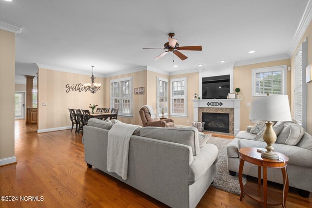 living room featuring a large fireplace, crown molding, baseboards, and wood finished floors