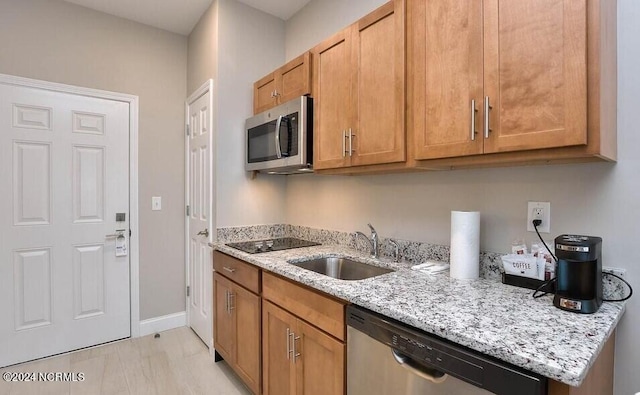 kitchen featuring stainless steel appliances, sink, and light stone counters