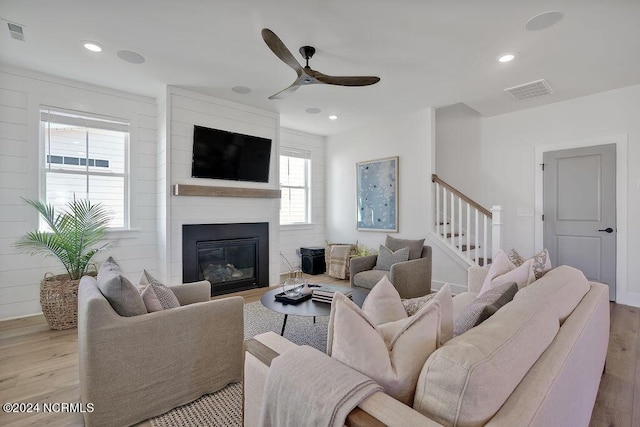 living room featuring a fireplace, ceiling fan, and light hardwood / wood-style flooring