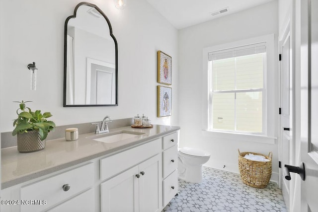 bathroom with toilet, a wealth of natural light, and vanity