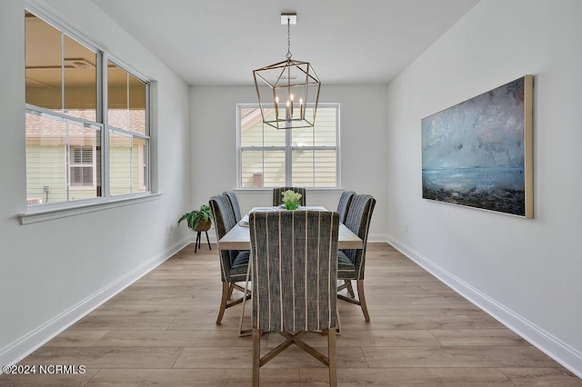 dining area with light wood-type flooring and an inviting chandelier