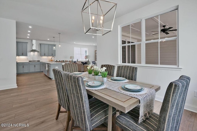 dining space with ceiling fan with notable chandelier and hardwood / wood-style floors