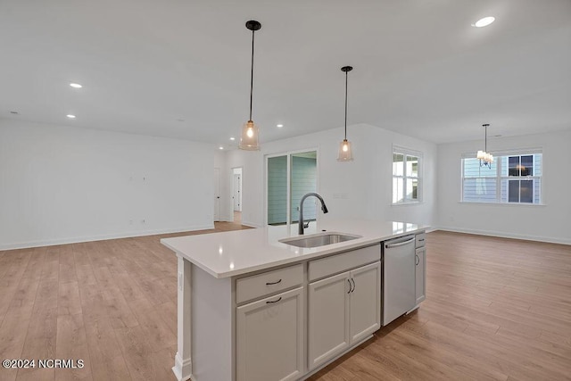 kitchen with stainless steel dishwasher, a center island with sink, sink, and light wood-type flooring