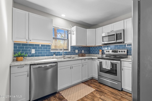 kitchen featuring appliances with stainless steel finishes, tasteful backsplash, sink, white cabinets, and dark hardwood / wood-style flooring