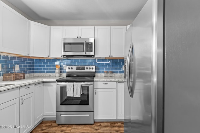 kitchen with dark hardwood / wood-style flooring, decorative backsplash, stainless steel appliances, and white cabinets