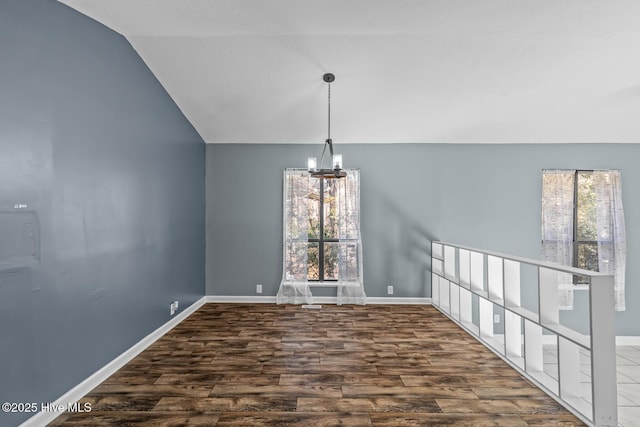 unfurnished dining area featuring a healthy amount of sunlight, lofted ceiling, dark hardwood / wood-style flooring, and a notable chandelier