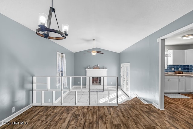 unfurnished dining area with hardwood / wood-style flooring, lofted ceiling, sink, and ceiling fan with notable chandelier