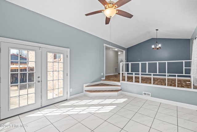 tiled spare room with french doors, ceiling fan with notable chandelier, and vaulted ceiling