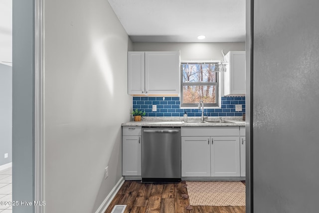 kitchen with tasteful backsplash, white cabinetry, dishwasher, sink, and dark wood-type flooring