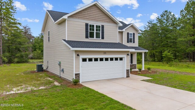 view of front of house featuring a front yard, central air condition unit, and a garage