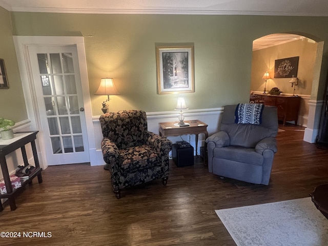 living area featuring arched walkways, dark wood-style flooring, and crown molding