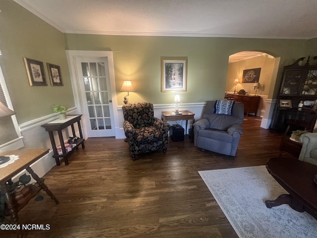 living area with arched walkways, ornamental molding, and dark wood-style flooring