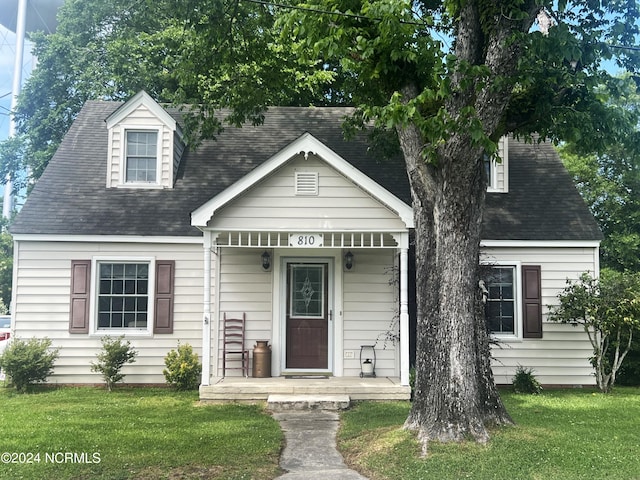 new england style home with covered porch and a front lawn