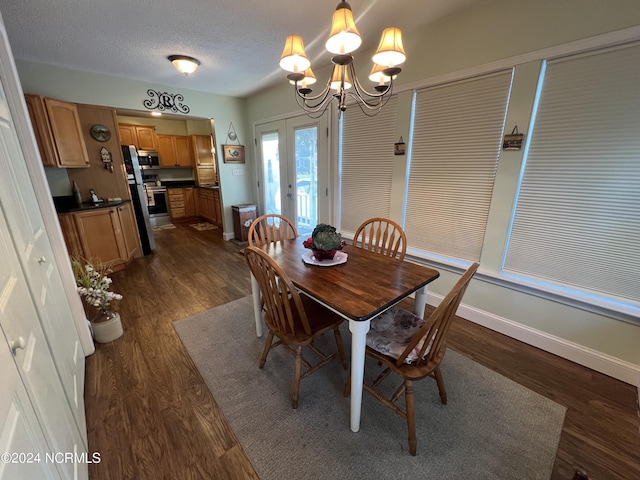 dining area featuring a textured ceiling, baseboards, french doors, dark wood finished floors, and an inviting chandelier