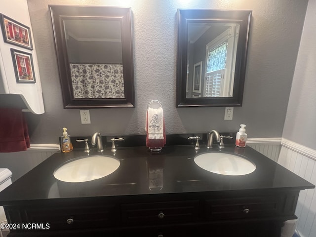 full bath with double vanity, wainscoting, and a sink