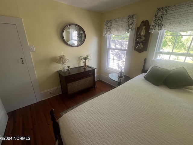 bedroom with baseboards and dark wood-type flooring