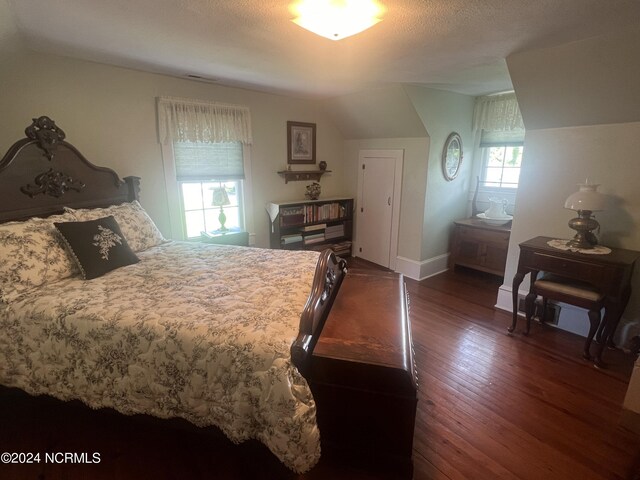 bedroom featuring vaulted ceiling, dark wood-type flooring, a textured ceiling, and baseboards