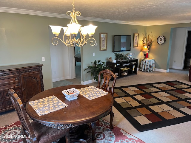 carpeted dining room featuring a textured ceiling, ornamental molding, and an inviting chandelier