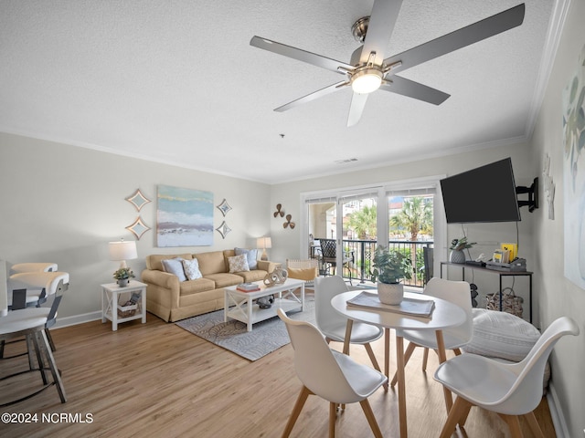 living room with a textured ceiling, ceiling fan, crown molding, and light wood-type flooring