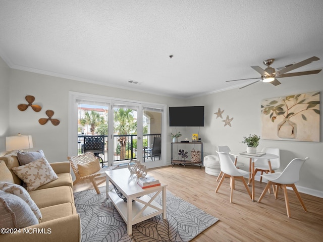 living room with crown molding, ceiling fan, a textured ceiling, and light wood-type flooring