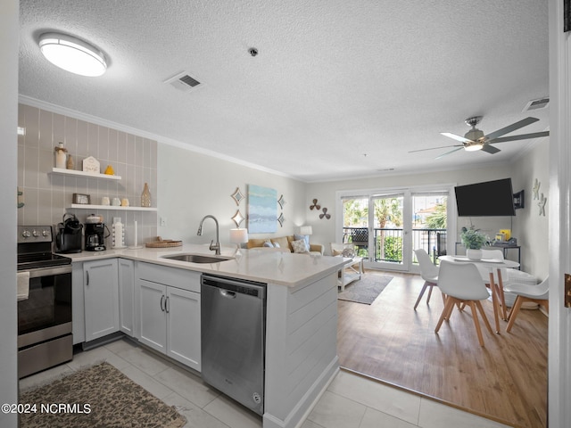 kitchen featuring kitchen peninsula, appliances with stainless steel finishes, light tile flooring, sink, and ornamental molding