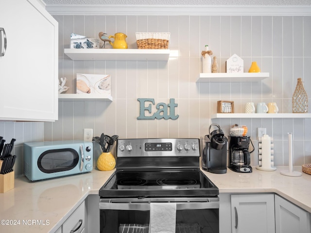 kitchen featuring stainless steel electric range, white cabinets, light stone counters, and crown molding