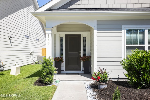 property entrance featuring central AC unit and a lawn