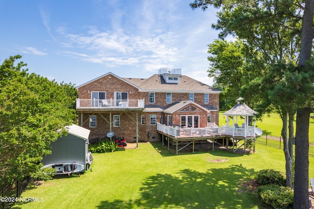 back of house featuring a gazebo, a yard, a deck, and a storage shed