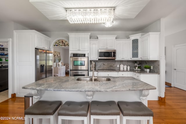 kitchen featuring white cabinets, appliances with stainless steel finishes, a center island with sink, and wood-type flooring