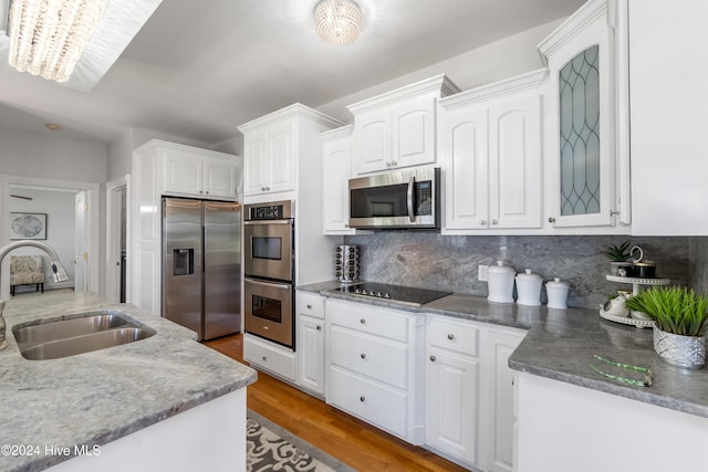 kitchen featuring stainless steel appliances, sink, wood-type flooring, an inviting chandelier, and white cabinets