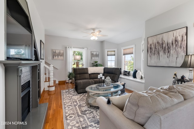 living room featuring hardwood / wood-style floors, plenty of natural light, ceiling fan, and a tile fireplace