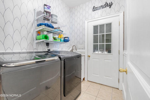 clothes washing area featuring washing machine and dryer, sink, light tile patterned floors, and cabinets