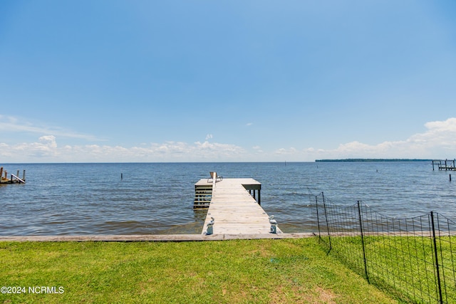 view of dock featuring a lawn and a water view