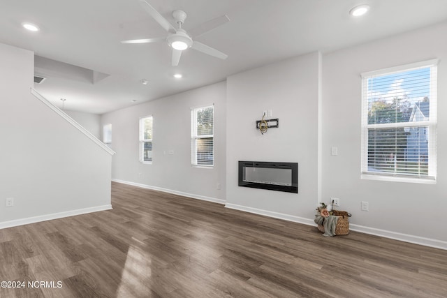 unfurnished living room with wood finished floors, recessed lighting, a glass covered fireplace, and baseboards