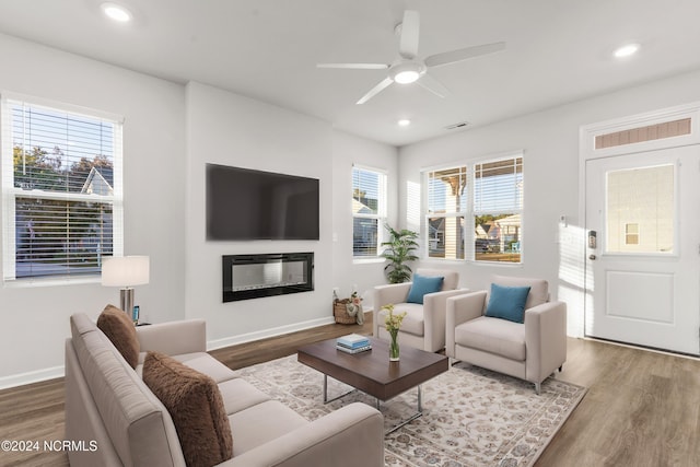 living room featuring recessed lighting, baseboards, wood finished floors, and a glass covered fireplace