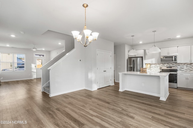 kitchen featuring a center island, light countertops, appliances with stainless steel finishes, open floor plan, and wood finished floors