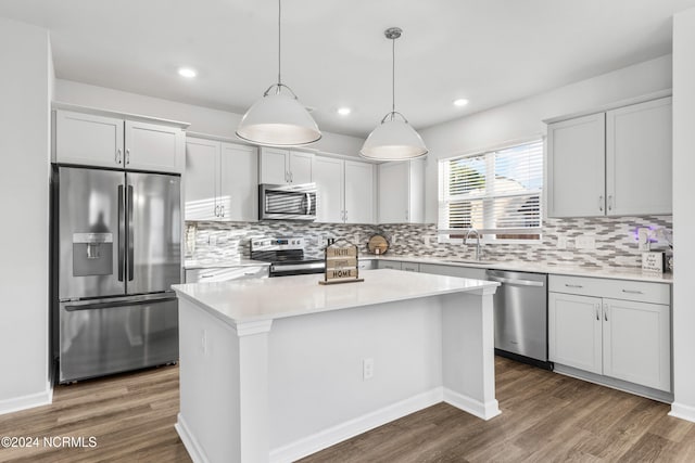 kitchen with dark wood-style floors, light countertops, appliances with stainless steel finishes, a sink, and a kitchen island